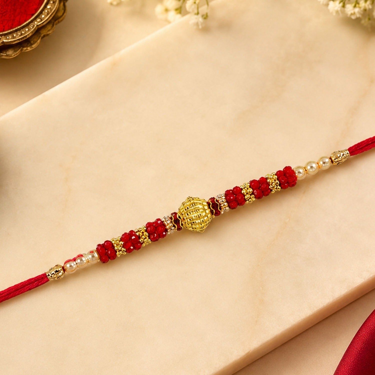ALVENZA Red Bead Rakhi – Golden Centerpiece & Pearl Details