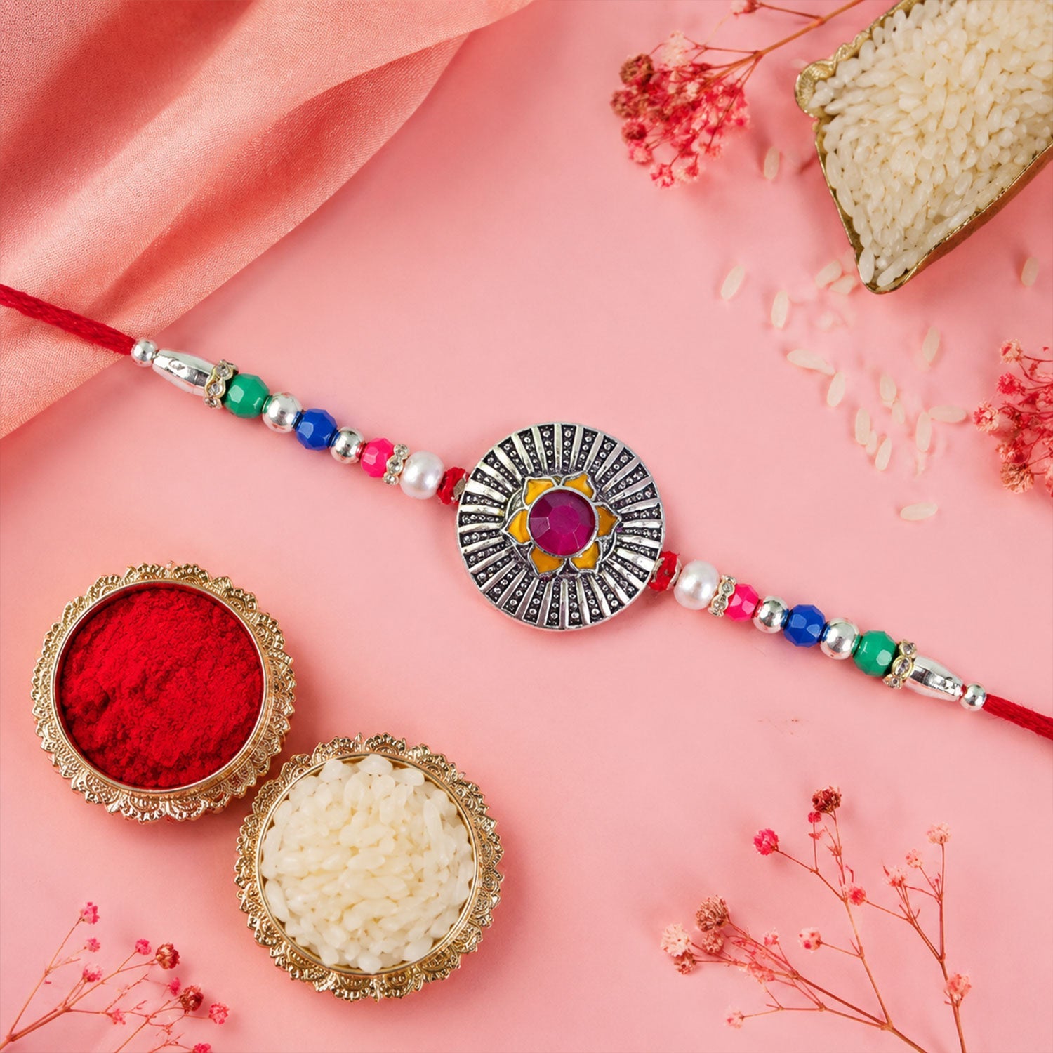 ALVENZA Sunburst Stone Rakhi with Magenta Centre, Pearl Beads, Roli Chawal Coin and Card Packing