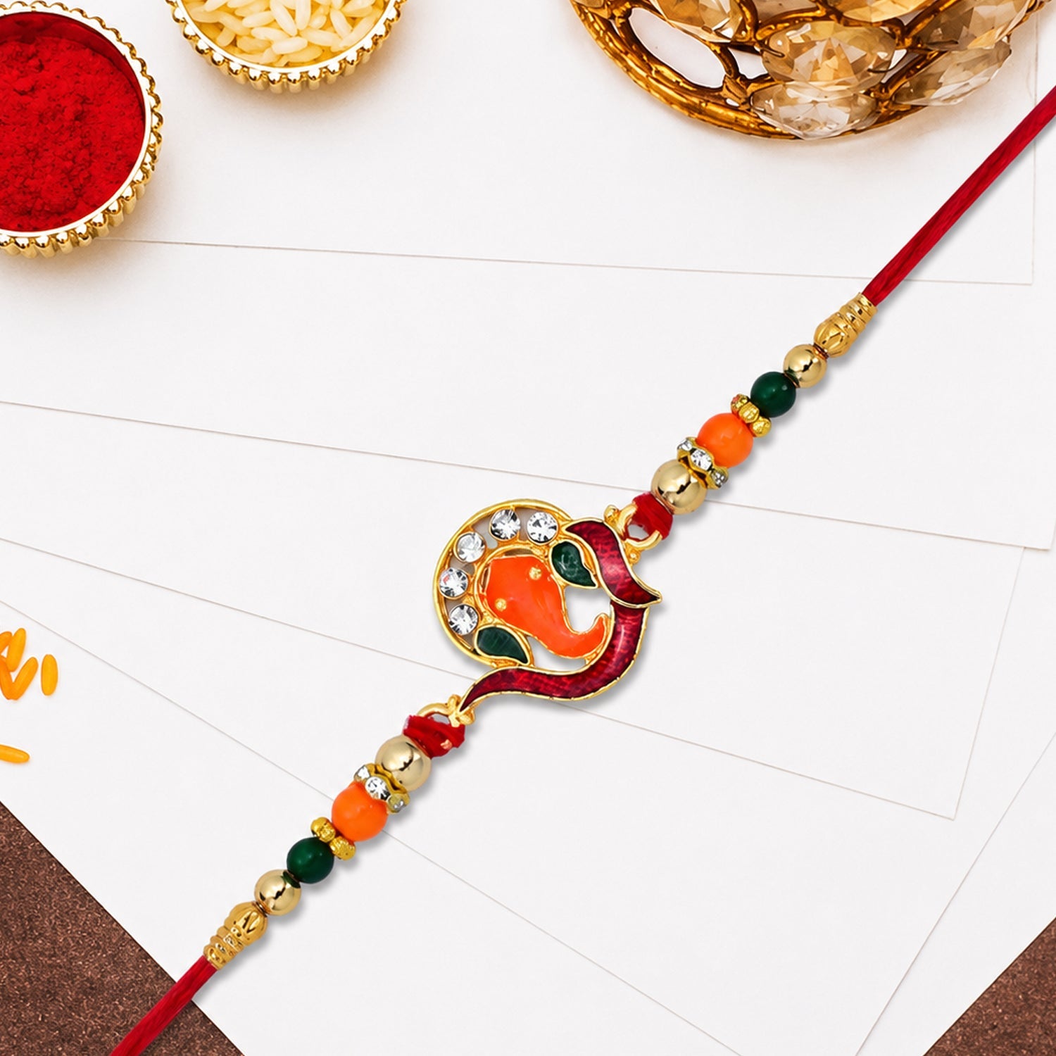 ALVENZA Golden Ganesha Rakhi – Red-Green Beads & Stone Detailing for Brother